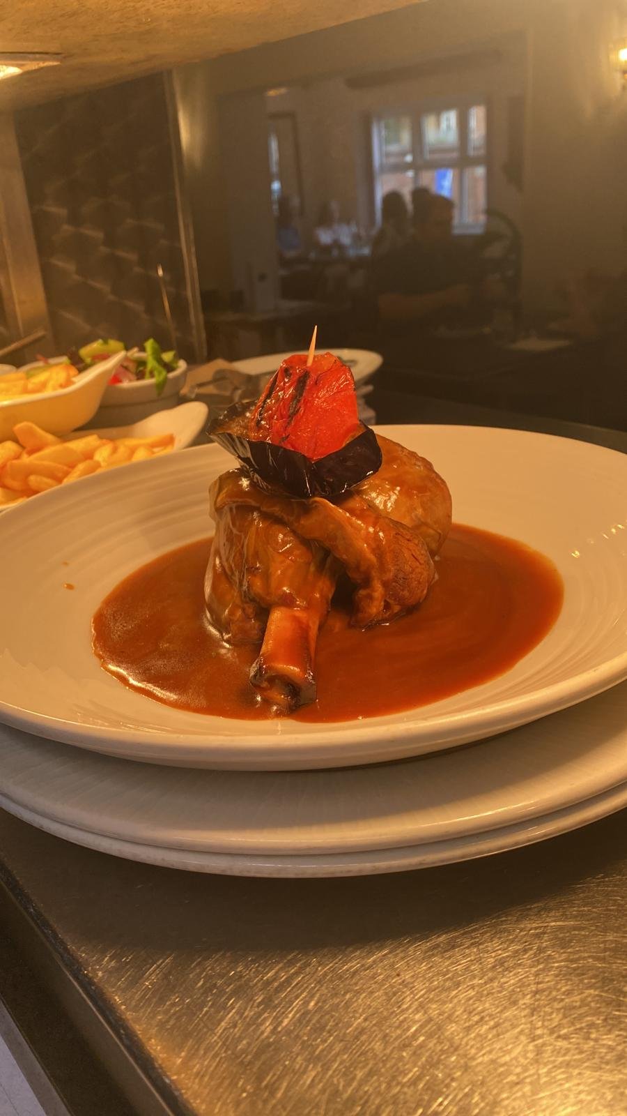 Slow-braised lamb shank in a rich jus with charred pepper garnish
