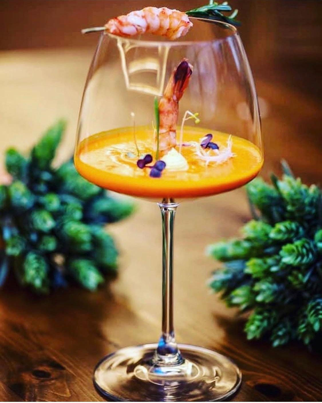 Prawn bisque served in a wine glass with micro-herbs